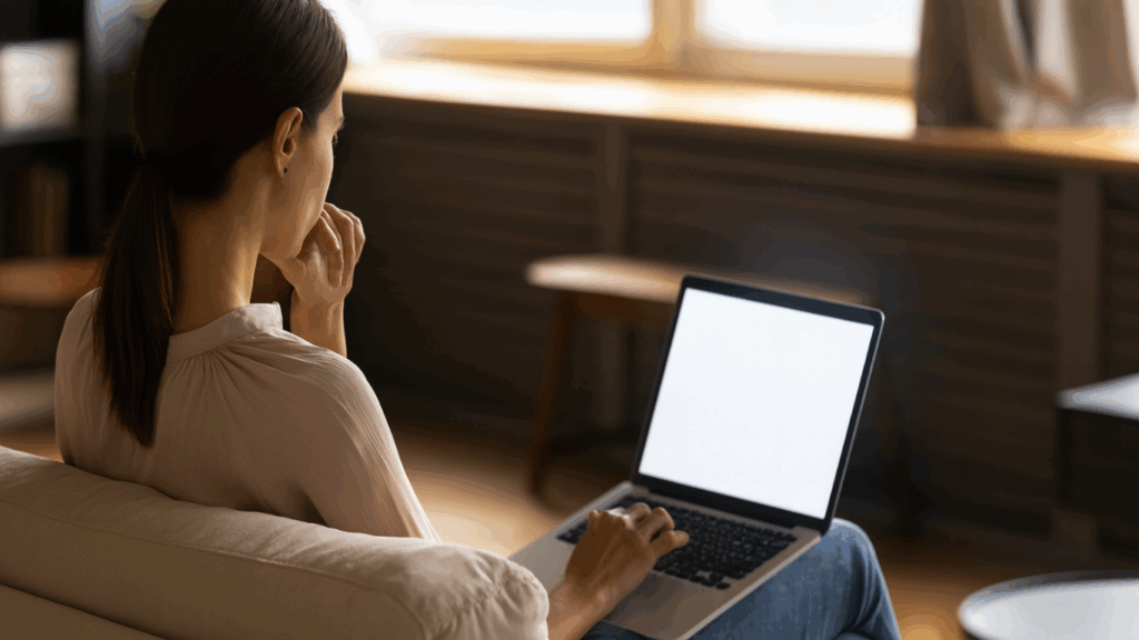 学習・リサーチ中の女性の後ろ姿。ピンクのブラウスの女性がノートPCで作業する様子